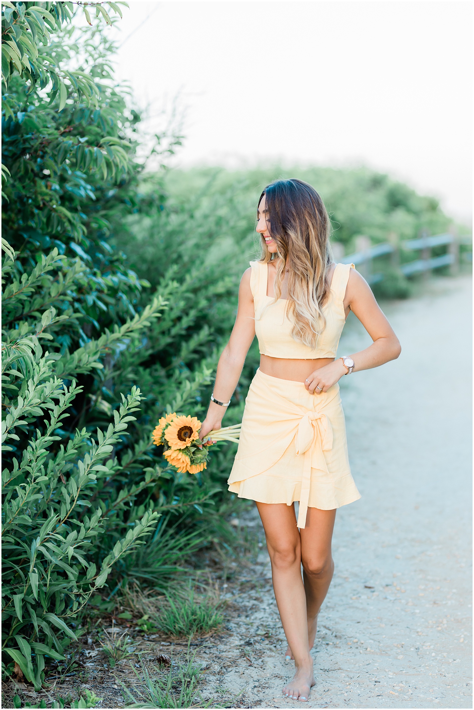 teen girl walking with sunflowers on the beach