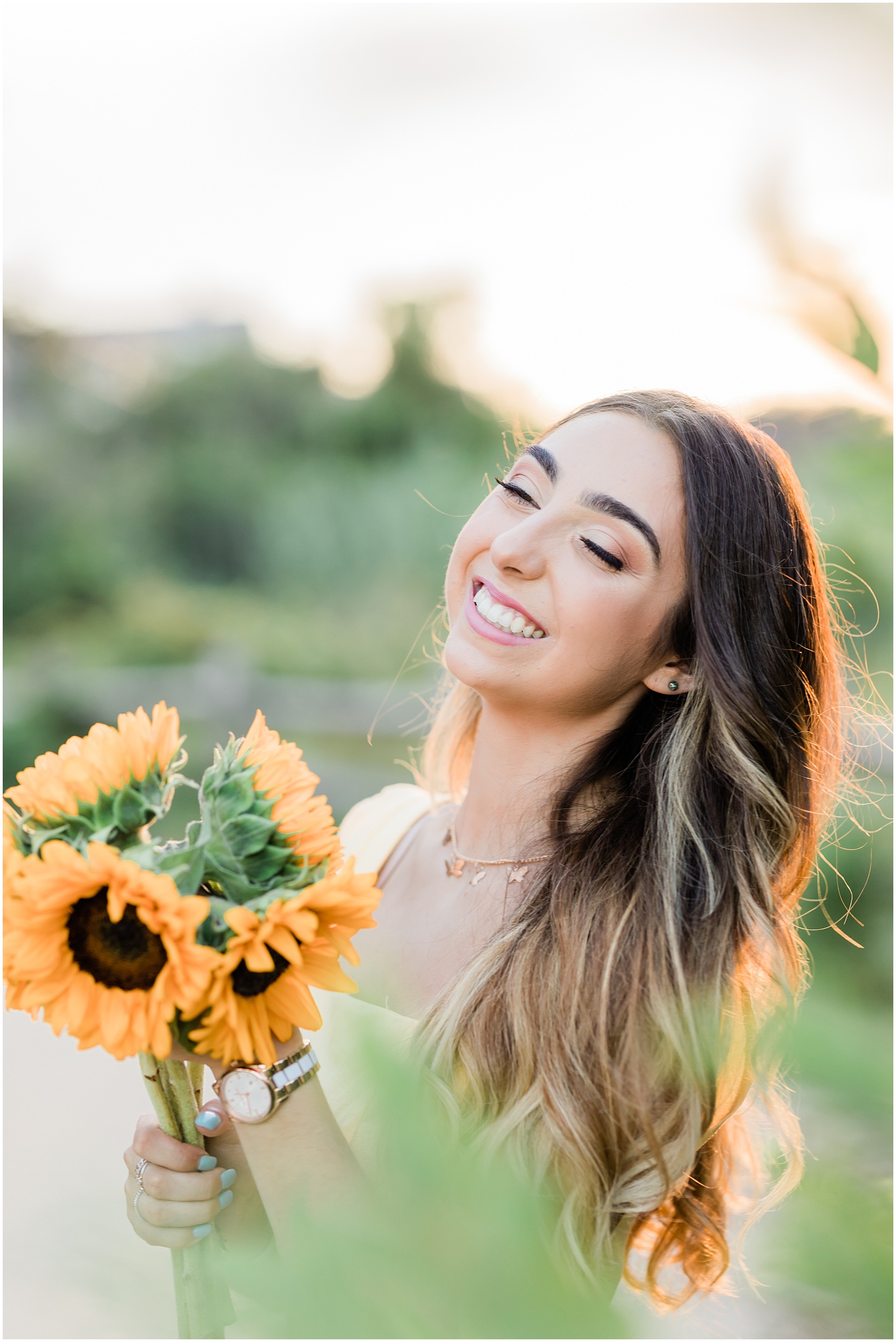 teen girl wearing a yellow skirt posing and smiling in a garden for her senior pictures