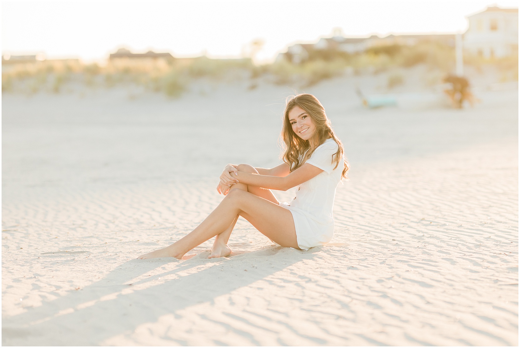 high school senior posing for senior pictures on the beach in ocean city new jersey. she is wearing a white romper. The sun is golden!