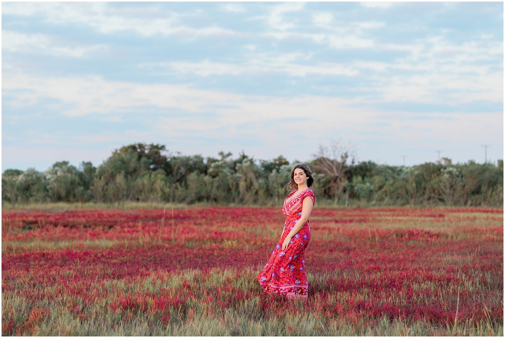 teen girl in red dress skipping through a field of red flowers near the beach in ocean city, nj