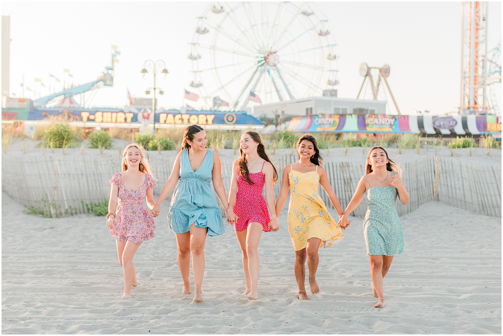 teen girls walking on the beach in front of a ferris wheel
